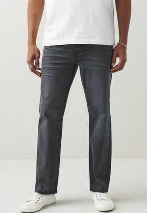 Donkergrijze jeans met een slim fit, met een gladde twill textuur en subtiele vervaging. Gecombineerd met witte sneakers voor contrast.