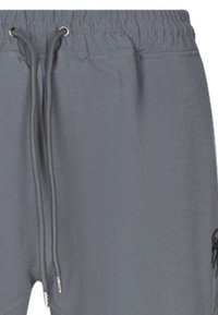 Pantalones de chándal grises con cintura elástica, cordones ajustables y un logo en el lateral. Textura suave y ajuste casual para mayor comodidad.