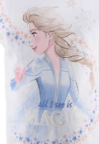 Tela blanca con un gráfico de un personaje con cabello rubio y atuendo azul, rodeado de estrellas de colores y texto que dice "todo lo que veo es MAGIA".