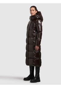 Pikk, tumepruun läikiva viimistlusega toppitud mantel, millel on kapuuts, lukuga taskud ja polsterdatud disain. Kandmiseks koos mustade põlveni ulatuvate saapadega.