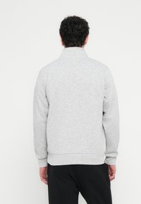 Γκρι φούτ�ερ με ψηλό γιακά, ριμπ μανσέτες και τελείωμα. Μαλακή υφή και άνετη εφαρμογή, εμφανίζεται από πίσω με φόντο λευκό.