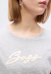 Γκρι T-shirt με στρογγυλή λαιμόκοψη διαθέτει υφασμένο, κρεμ χρώματος λογότυπο «Boss» σε καλλιγραφική γραφή. Μαλακό ύφασμα με χαλαρή εφαρμογή.