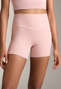 Ružové športové šortky vyrobené z elastického materiálu, s vysokým pásom a hladkou textúrou, s priliehavým strihom.