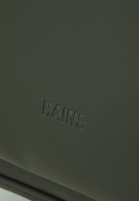 Mörkgrön vattentät väska med en slät yta, försedd med en präglad logotyp "RAINS." Minimalistisk design utan synlig hårdvara eller detaljer.