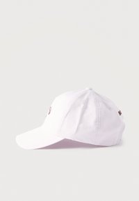 Λευκό βαμβακερό καπέλο μπέιζμπολ με καμπυλωτό γείσο, ορατή ραφή και κεντημένο κείμενο που διακρίνεται μερικώς στο πλάι.