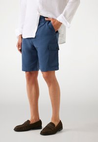 Shorts cargo bleus en tissu léger, dotés d'une poche latérale avec un bouton, coupe droite et longueur au-dessus du genou.