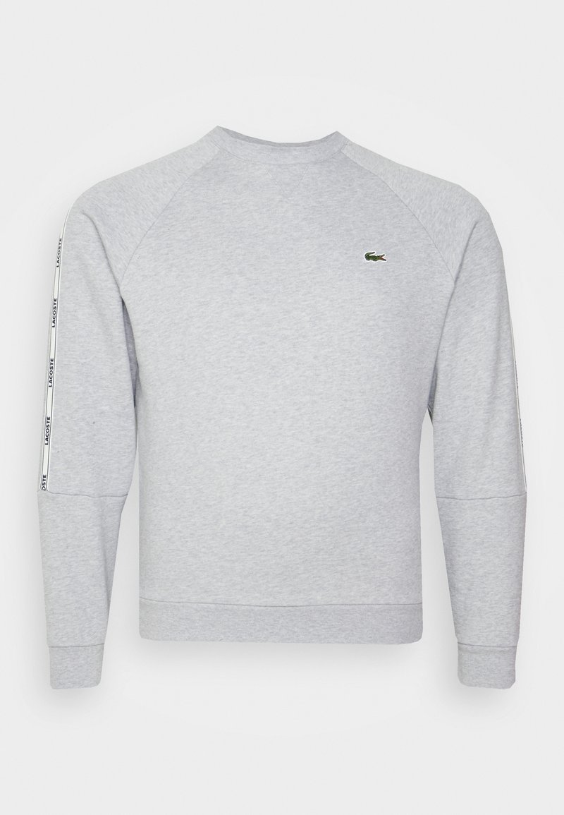 Sweat-shirt gris avec poignets et encolure côtelés, présentant un petit logo vert sur la poitrine et une bande blanche sur les côtés avec un motif de texte.