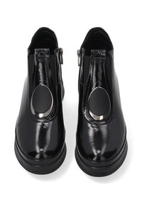 Černé lesklé kotníkové boty se zaoblenou špičkou, bočním zipem a velkým oválným akcentem. Hladký povrch a robustnější design podrážky.