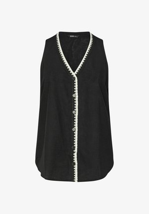 Sort ærmeløs top med V-hals, som har hvid bølget trim langs halslinjen og knaplukning foran, lavet af letvægtsstof.