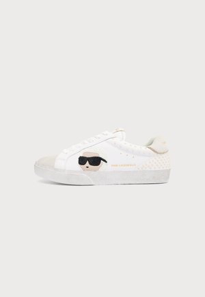 Λευκό χαμηλό sneakers με μπεζ κάλυμμα δακτύλων, τρουκς στη φτέρνα και καρικατούρα προσώπου με μαύρα γυαλιά ηλίου στο πλάι, με σήμανση Karl Lagerfeld.