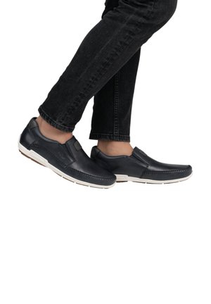 Marineblauwe leren instapschoenen met witte rubberen zolen, voorzien van gestikte details en een platte uitstraling, gedragen met zwarte jeans.
