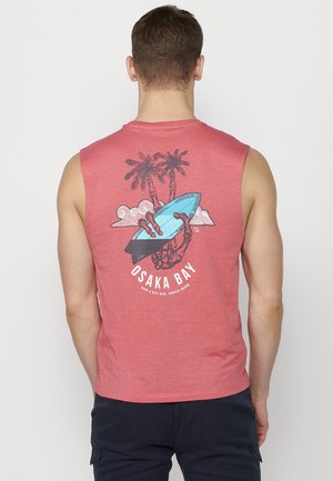 Camiseta sin mangas roja con un estampado gráfico de palmeras, un surfista y una tabla de surf. Material de algodón con una textura suave.