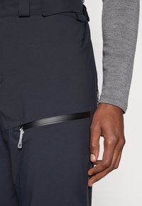 Νάυτικο παντελόνι αδιάβροχο στον άνεμο με υφή στο ύφασμα, που διαθέτει οριζόντια τσέπη με φερμουάρ και ασφαλή τράβηγμα φερμουάρ.