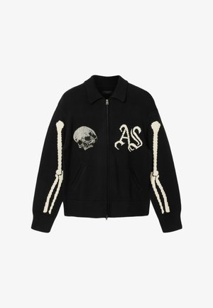 Maglione nero con cerniera, con teschio bianco e scritta "AS" sul davanti, e motivi di ossa bianche lungo entrambe le maniche.