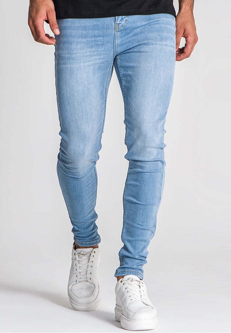 Ljusblå denimjeans med smal passform, som har en klassisk design med fem fickor, subtila blekningar och kombinerade med vita sneakers.