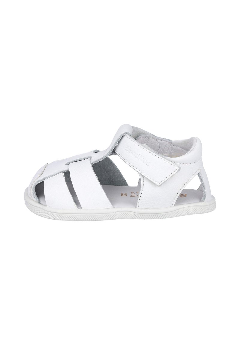 Sandalias de cuero blanco con múltiples recortes, cierre de tira de Velcro y plantilla texturizada para mayor comodidad. Suela plana de goma.