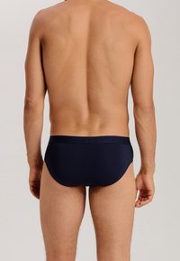 Slip azzurro navy con una texture liscia e un elastico in vita con branding in rilievo. Taglio basic con copertura totale sul retro.