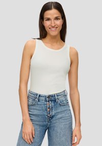 Top senza maniche grigio chiaro con scollatura rotonda, abbinato a jeans in denim blu chiaro a vita alta con chiusura a bottoni.