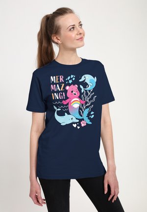 Granatowa koszulka z zabawną grafiką przedstawiającą różowego syrenka-niedźwiedzia i delfiny, napis "MERMAZING!" w kolorowych literach, gładki materiał.
