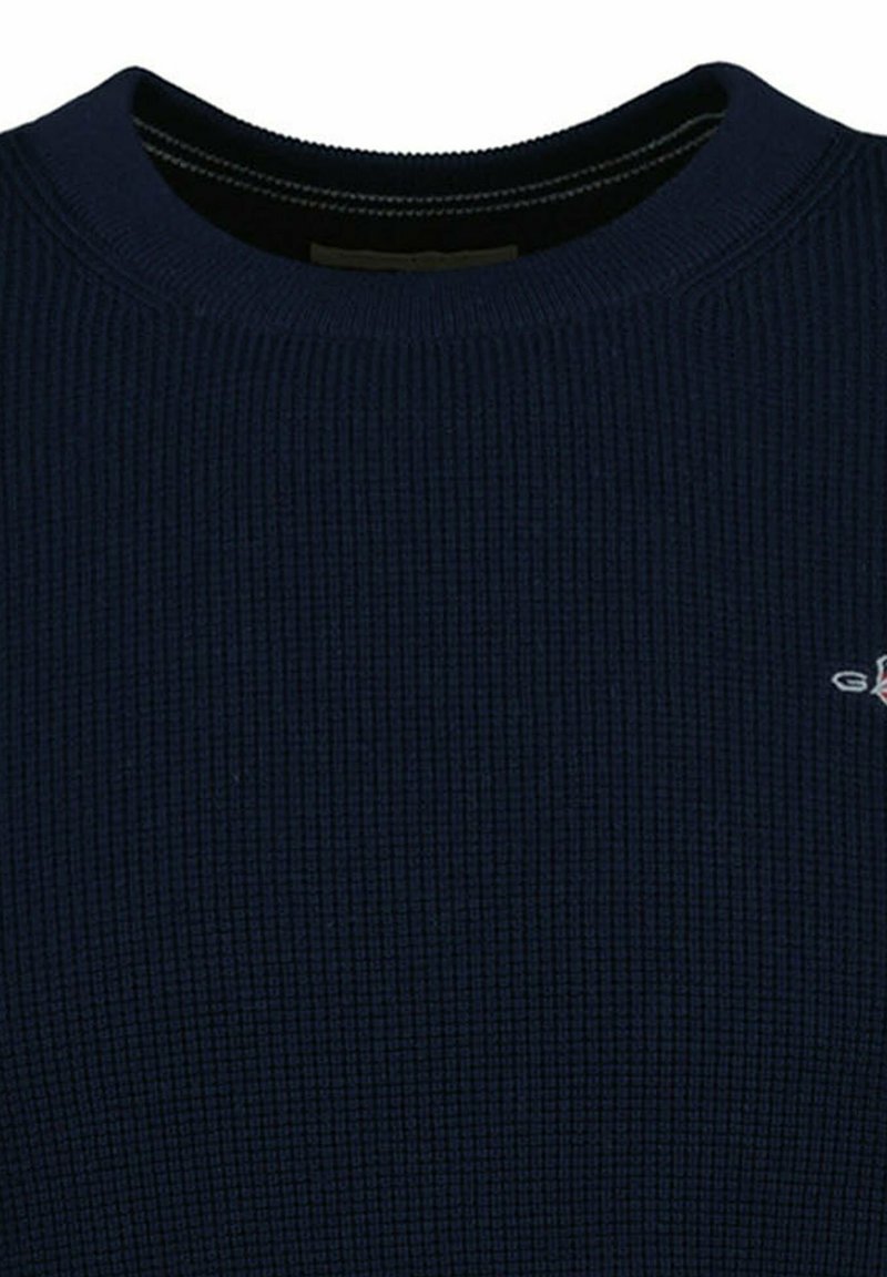 Maglione a coste di colore blu navy con scollo rotondo e sottile dettaglio del logo ricamato sul lato sinistro del petto. Tessuto morbido e strutturato.