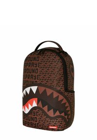 Mochila marrón con un atrevido diseño de tiburón que presenta dientes blancos y rojos; fabricada con material duradero; incluye detalles en negro y un asa en la parte superior.
