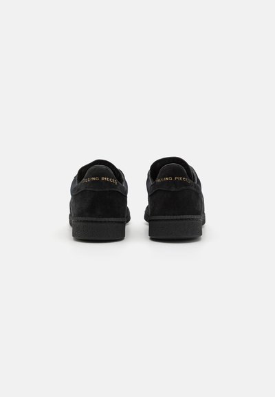 Black suede sneakers with a textured rubber sole, featuring a round toe and subtle branding on the heel. Back view shows smooth leather accents.
