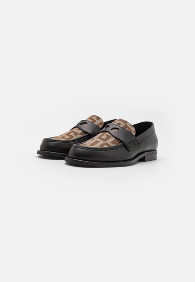 Schwarze Leder-Loafers mit einem braunen, gemusterten Stoffeinsatz. Mit einem dekorativen Riemen und einem niedrigen, gestapelten Absatz.