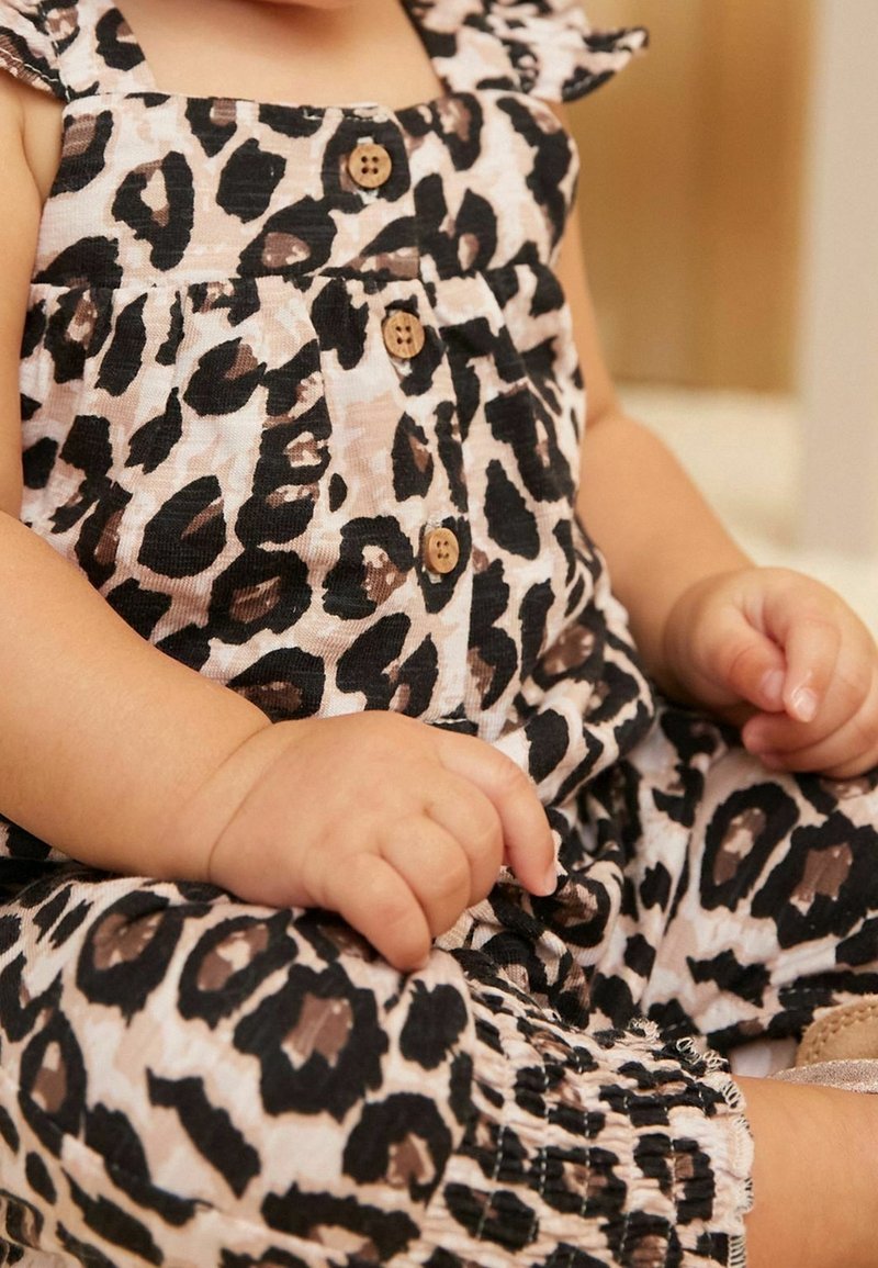 Luipaardprint romper van zachte stof, met een aansluitend lijfje, ruffle schouderbanden, houten knopen en elastische manchetbanden. Kleurenpalet bevat bruintinten en zwart.