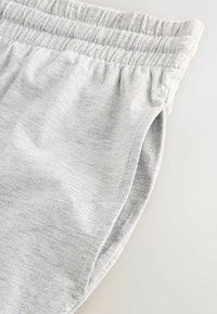 Svetlosivé bavlnené šortky s elastickým pásom, s jemnou textúrou a bočnými vreckami, navrhnuté pre pohodlie a ľahké nosenie.