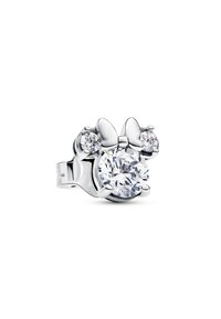 Prsten strieborného tónu s veľkým centrálnym priehľadným drahokamom a dvoma menšími kameňmi na oboch stranách, zdobený detailom mašle.