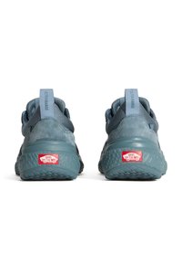 Blå sportskor med en texturerad gummisul. Överdel i mocking och mesh, bakre dragflik och röd "Off the Wall"-logotyp på hälen.