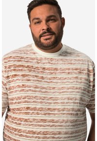 Košile s krátkým rukávem v krémové barvě a vlnitými hnědými pruhy. Měkký materiál a kulatý výstřih. Volný střih bez dalších detailů.