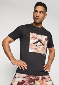 Svart bomull T-skjorte med et kvadratisk grafikk med en steinete tekstur og Nike-logotypen. Korte ermer og design med rund hals.