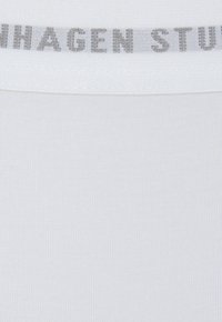 White seamless fabric with a smooth texture, featuring a gray elastic waistband with "COPENHAGEN STUDIOS" woven into it.