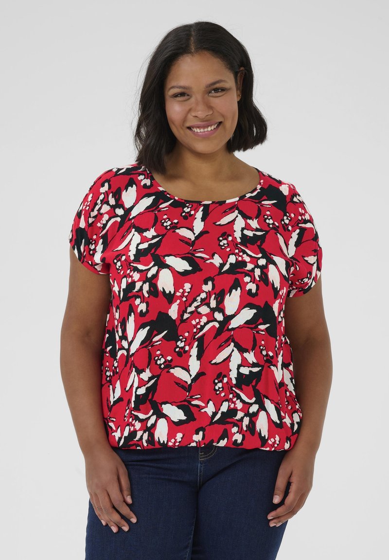 Blusa rossa a fiori con dettagli in bianco e nero, caratterizzata da un colletto tondo e maniche corte, realizzata in tessuto leggero e strutturato.