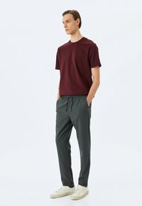 Bordeaux kortærmet t-shirt parret med grå taljebåndbukser og hvide sneakers. Enkel design med en afslappet pasform og blød tekstur.