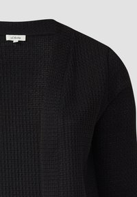 Cardigan noir tricoté avec texture gaufrée et devant ouvert, montrant l’étiquette de la marque s.Oliver à l’intérieur du col.