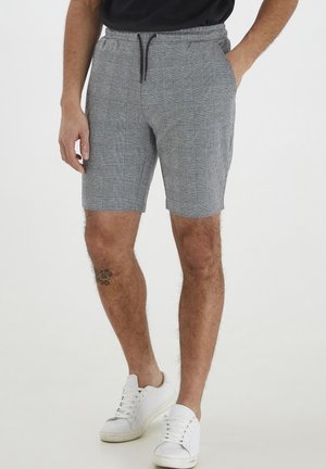 Gråternet shorts med elastisk talje og snøre. Har sidelommer og en afslappet pasform, parret med hvide sneakers.