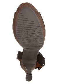 Semelle de chaussure marron avec caoutchouc noir texturé, présentant un motif géométrique et un marquage en relief. Le talon est solide avec un amorti minimal.