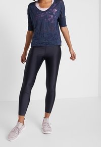 Námořnicky modrý poloprůhledný top s květinovým vzorem a krátkými rukávy, doplněný o černé matné legíny a světle růžové sportovní boty.