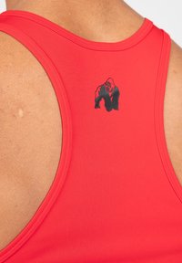 Rode sportieve tanktop met een grafische afbeelding van een zwarte gorilla op de achterkant, gemaakt van soepele, rekbare stof met een ronde halslijn en brede schouderbanden.