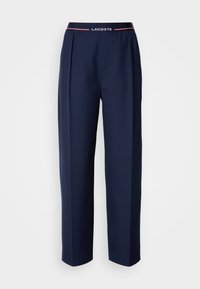 Pantaloni navy realizzati in tessuto liscio, con un design plissettato, gambe larghe e una vita con il logo Lacoste e dettagli rossi.