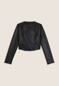 Giacca nera in finta pelle, corta, con maniche lunghe, cuciture minime e un piccolo etichetta sul colletto posteriore, su uno sfondo beige.