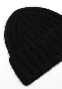 Gorro de punto negro con textura acanalada. Hecho de un material suave y peludo, con un puño doblado en la parte inferior.