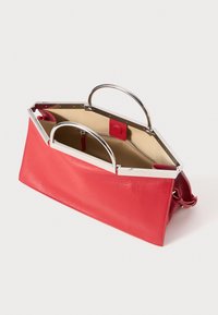 Rote Lederhandtasche mit silbernem Metallrahmen und Griffen, beigem Innenfutter und einer inneren Reißverschlusstasche, geöffnet auf weißem Hintergrund gezeigt.