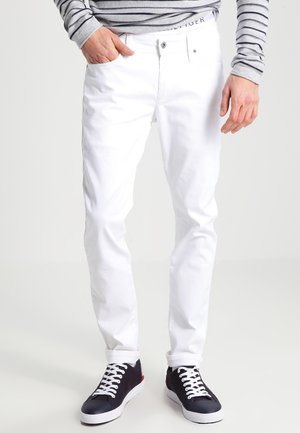 Vita bomullsjeans med smal passform, med femficksdesign och dragkedja. Matchas med mörka sneakers och en grårandig långärmad tröja.