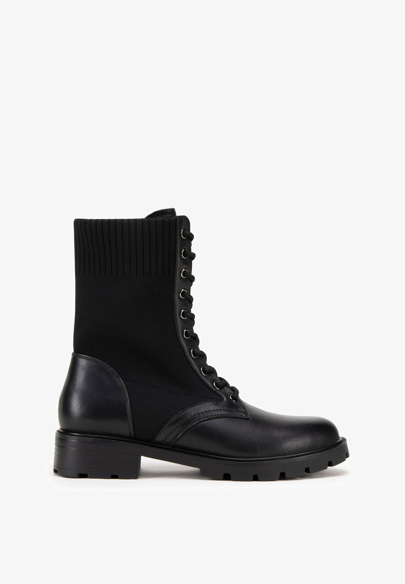 Botines negros que combinan material de cuero y punto acanalado, con puntera redonda, cierre de cordones en la parte delantera y un tacón bajo tipo bloque.