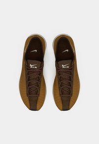 Rjave perforirane teniske z temno rjavimi detajli in vezalkami. Imajo belo Nike logotip in teksturiran podplat. Zasnova z zaobljenim nosom.