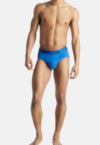 Blå mäns kalsonger med ett svart elastiskt midjeband som har tre ränder. Tillverkade av ett mjukt, stretchigt material för komfort och passform.