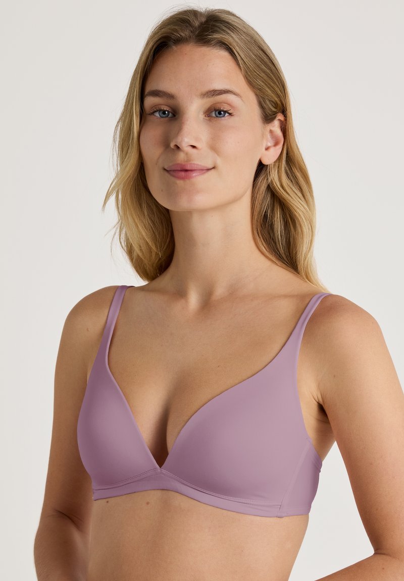 Light purple seamless bra with a deep V-neck, adjustable thin straps, and a smooth texture. No visible hardware or embellishments.